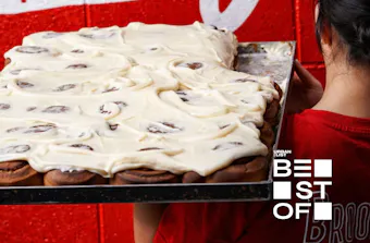 a person holding a tray of cinnamon scrolls