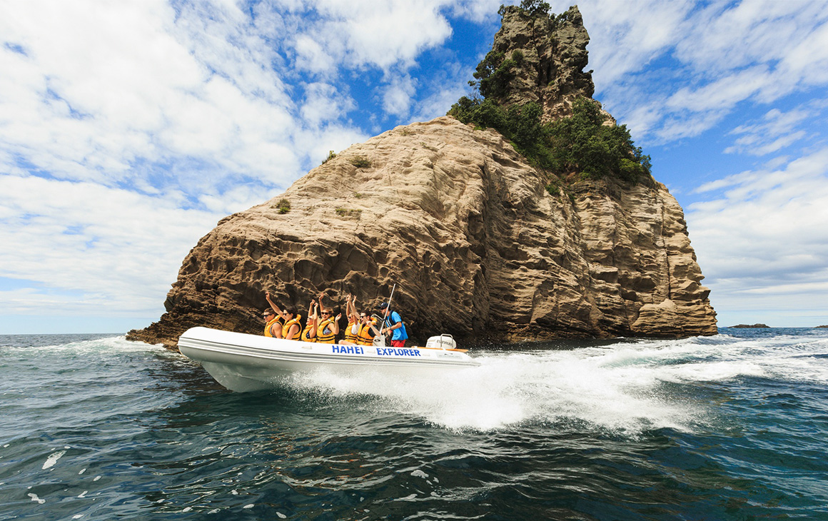 A small boat of people cruise over the water at Cathedral Cove