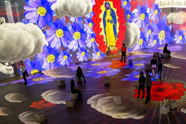 People walking in a vibrant Frida Kahlo art exhibition in Sydney. 