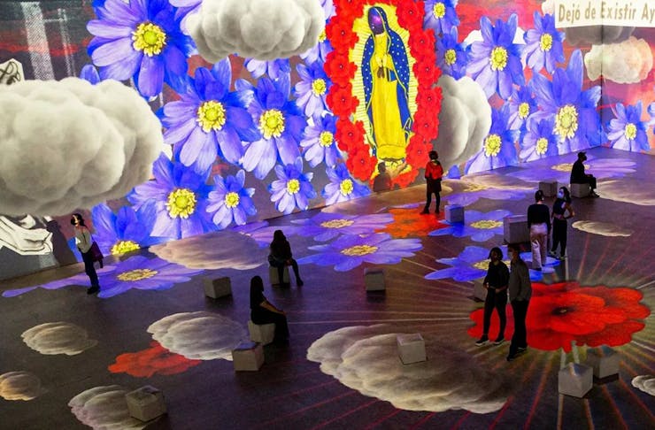 People walking in a vibrant Frida Kahlo art exhibition in Sydney. 