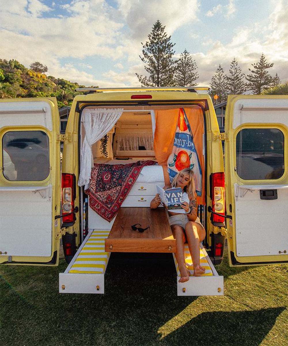 A woman sits in the open back of the Dolce Sole Camper