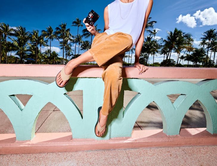 Woman sitting on bright coloured bench wearing FitFlop sandals