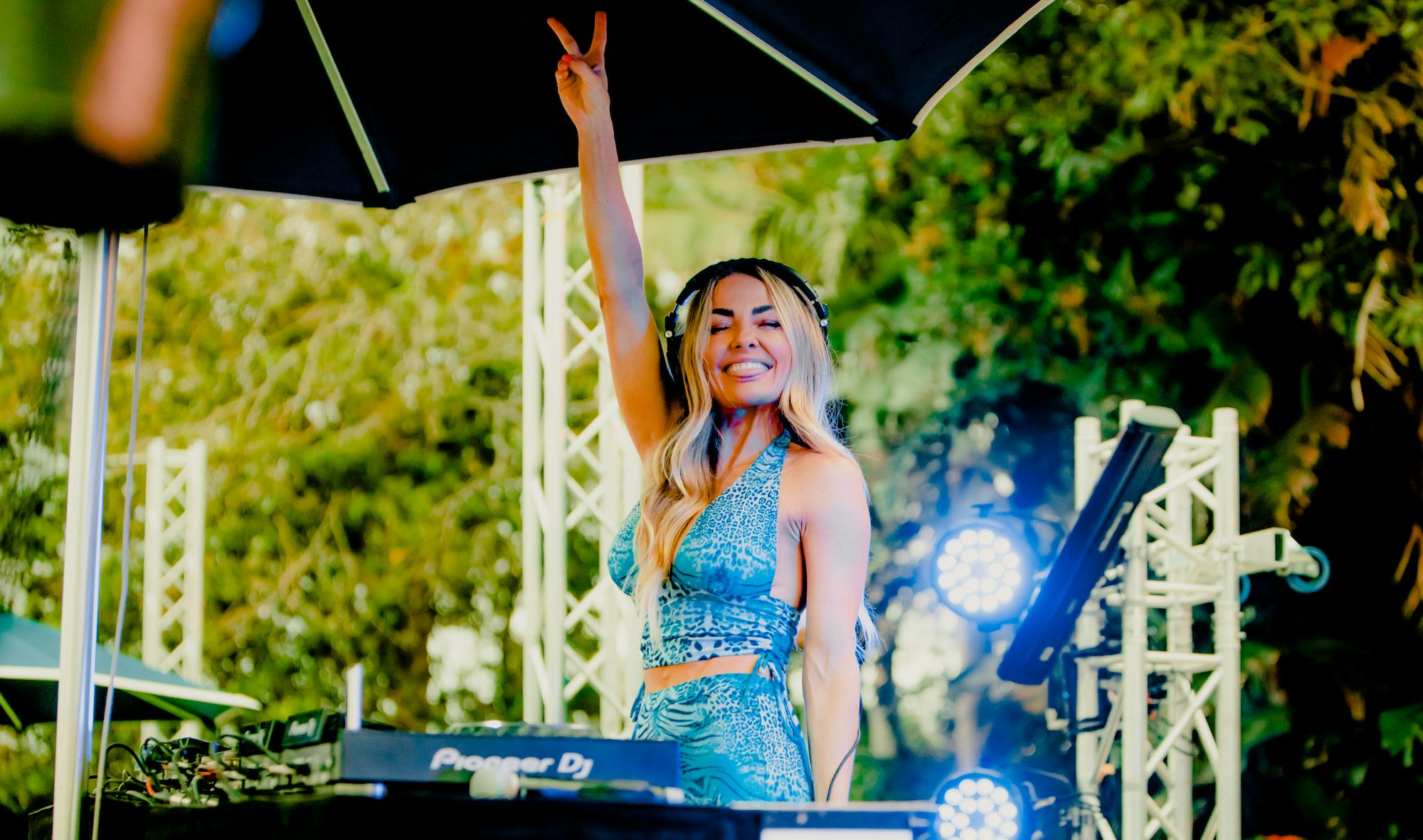 person at a DJ desk with their hand in the air