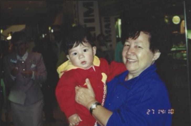 an older person holding a baby and smiling at night markets