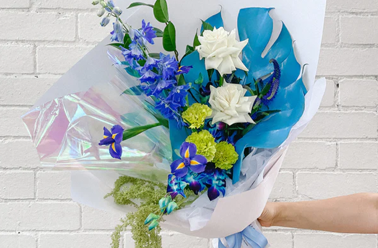 A person holding a stunning bunch of vibrant blue flowers from a Melbourne flower delivery service, Hello Blooms