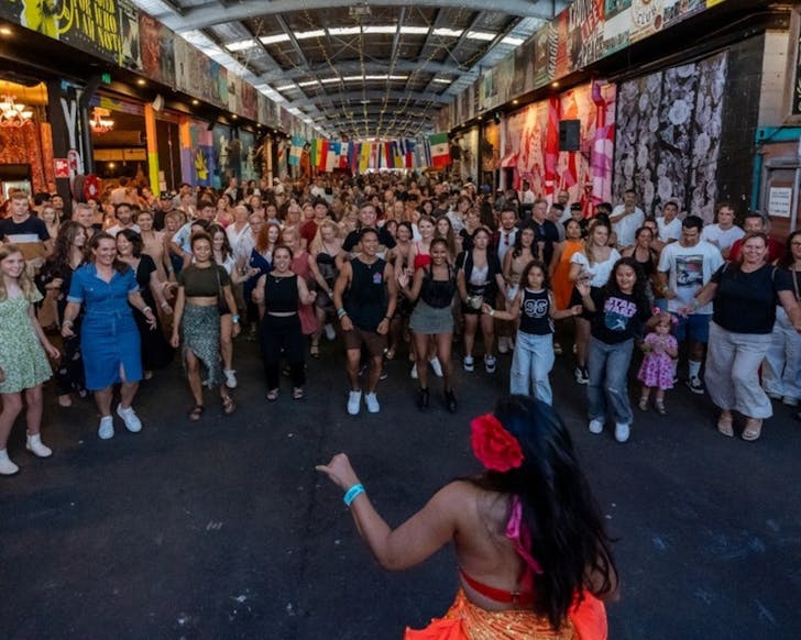 A lady dressed in a salsa dancing outfit dances in front of a large crowd.