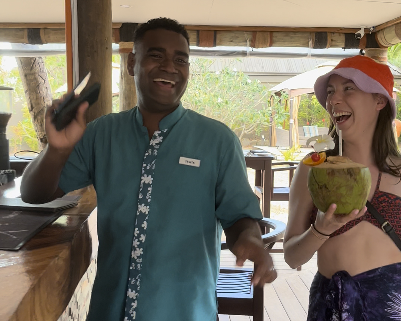 Laughing with the staff at Paradise Cove Resort while holding a fresh coconut