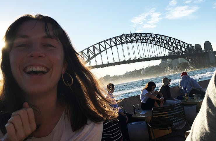 Girl standing and smiling in front of the Sydney Harbour Bridge for NYE. 