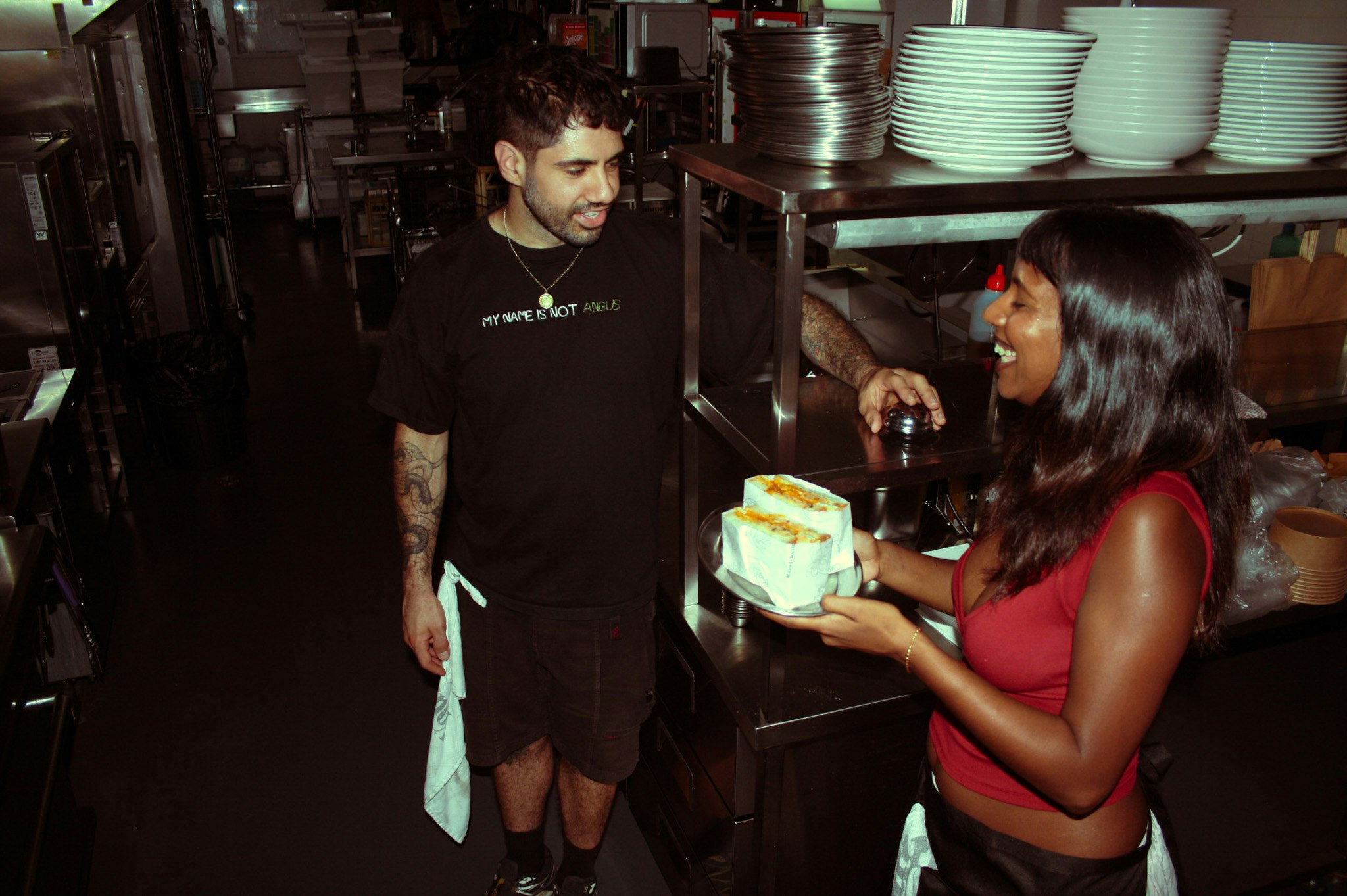 two people in a commercial kitchen, having a moment and laughing together