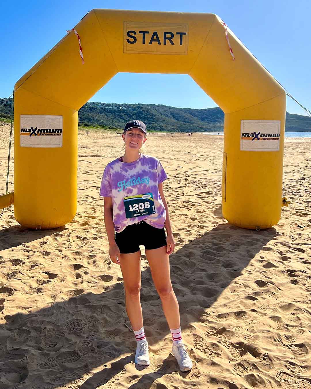 Elise after running a half marathon, standing at the finish line on a beach