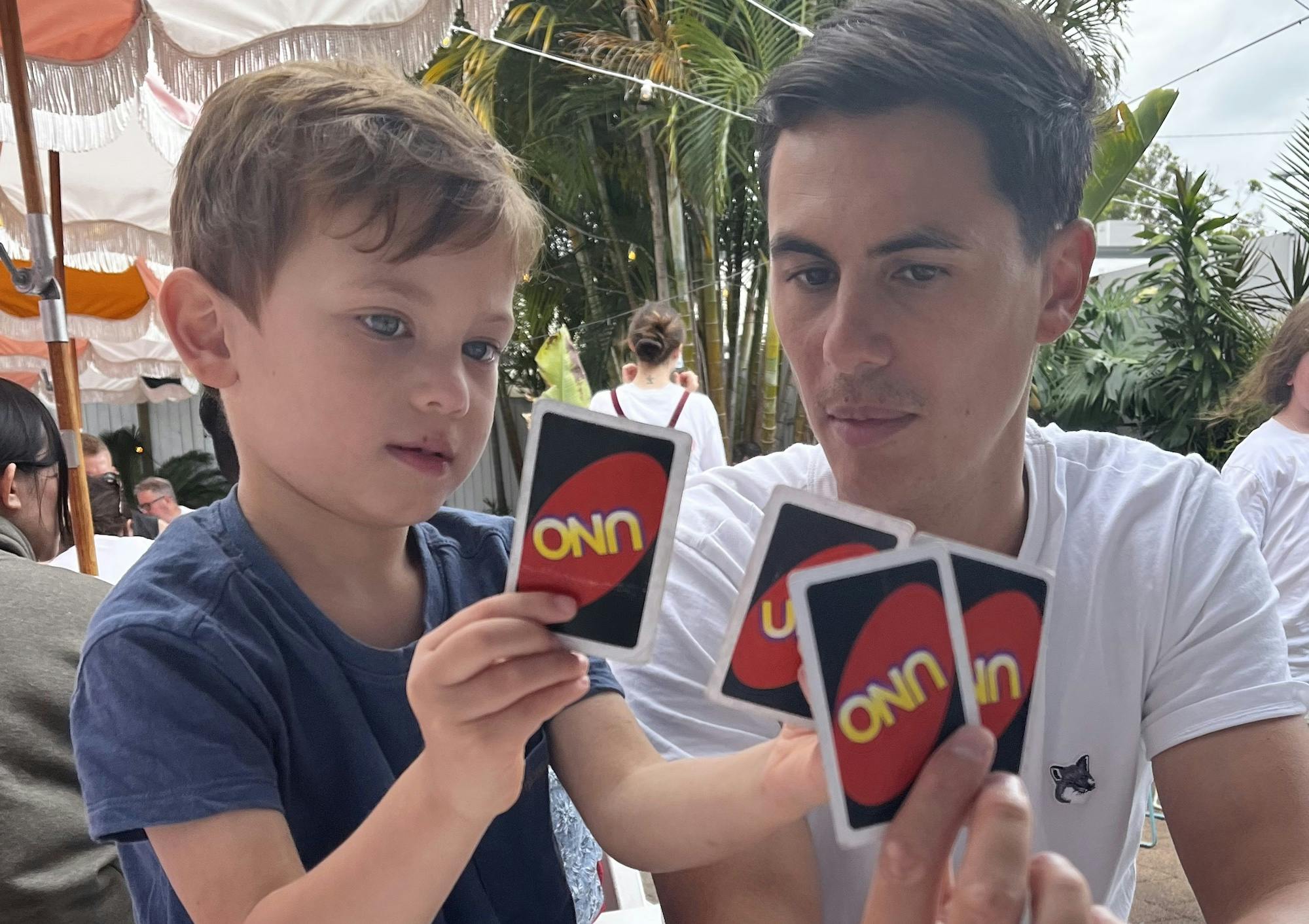 A dad and his kid playing Uno at a restaurant table