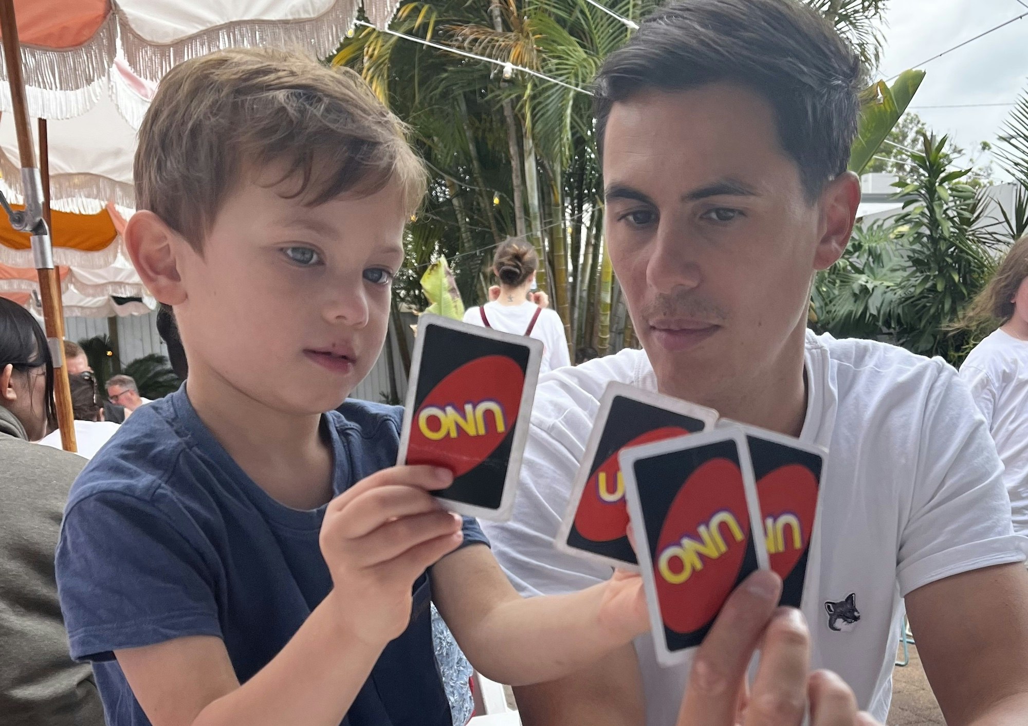 A dad and his kid playing Uno at a restaurant table