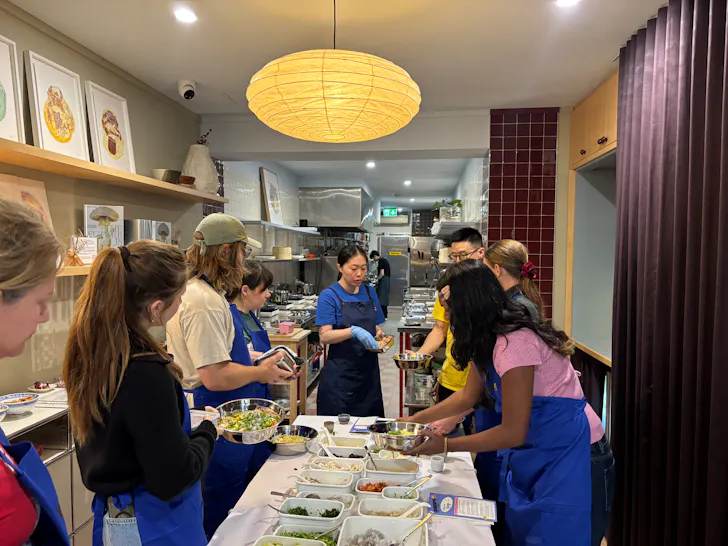 people gathered around a table making dumplings in a shop