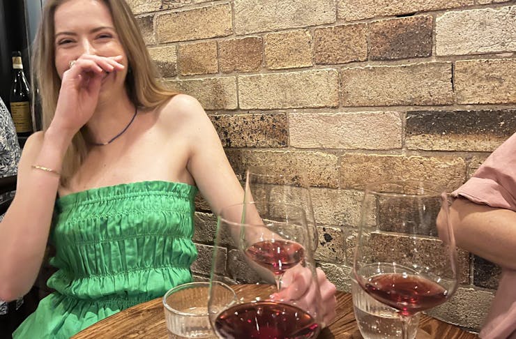 A person siting a table laughing with chilled red wine on the table
