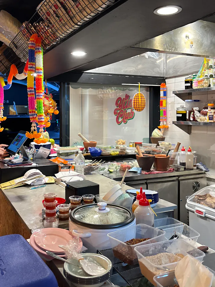 a restaurant counter with a rice cooker, plastic containers and sauce bottles