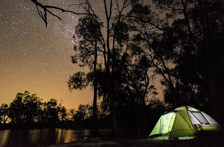lit up tent beside river in murray river national park campground