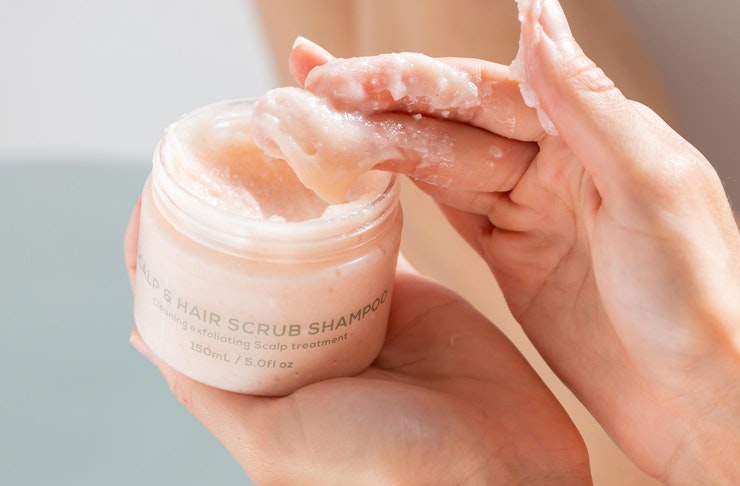 hand scooping up hair scrub from small jar
