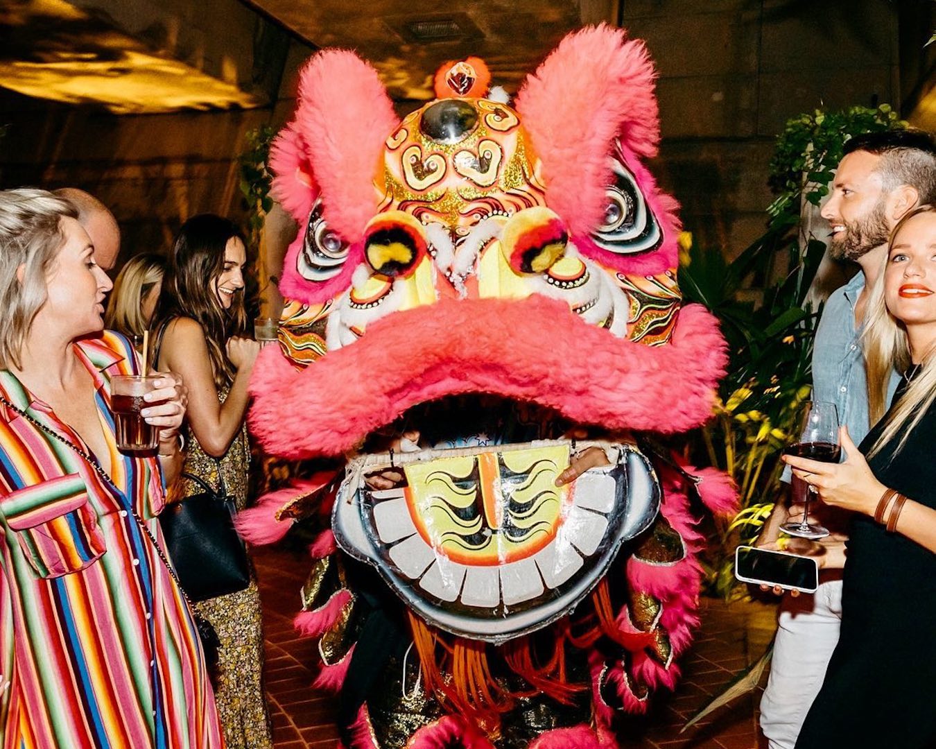 A traditional lion dancer approached the camera surrounded by people dancing.
