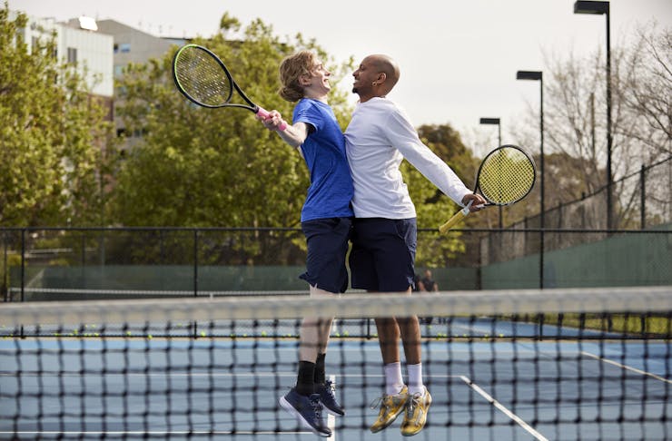 Two men chest pumping on a tennis court. 