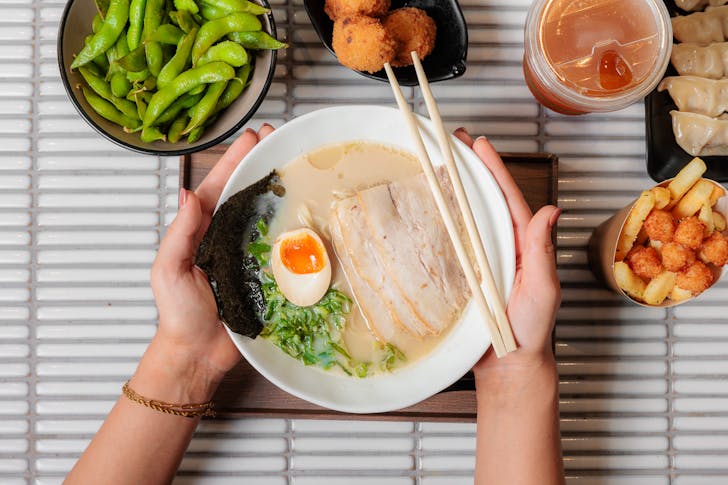 a bowl of ramen with other bowls of food around it