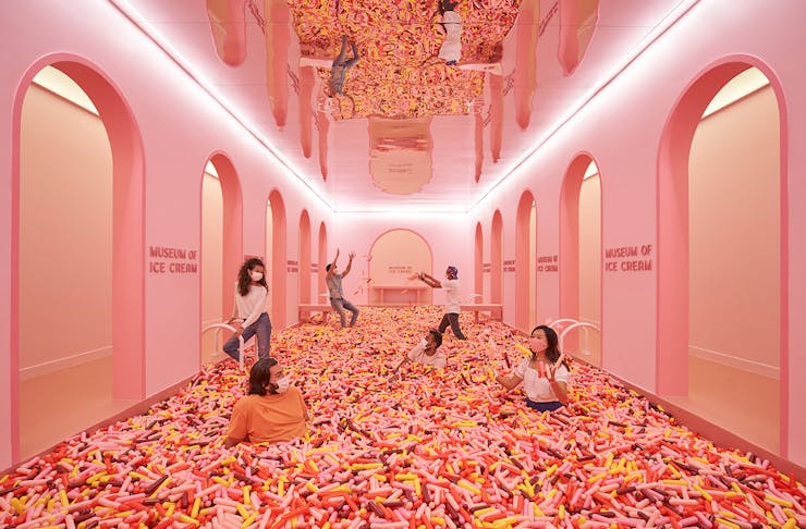 A room full of giant sprinkles in a type of ball pit with people in it.