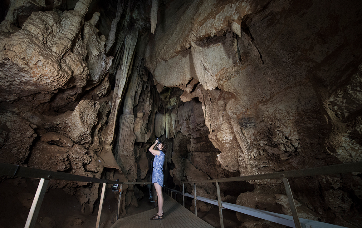A woman takes a photo at Cutta Cutta Caves