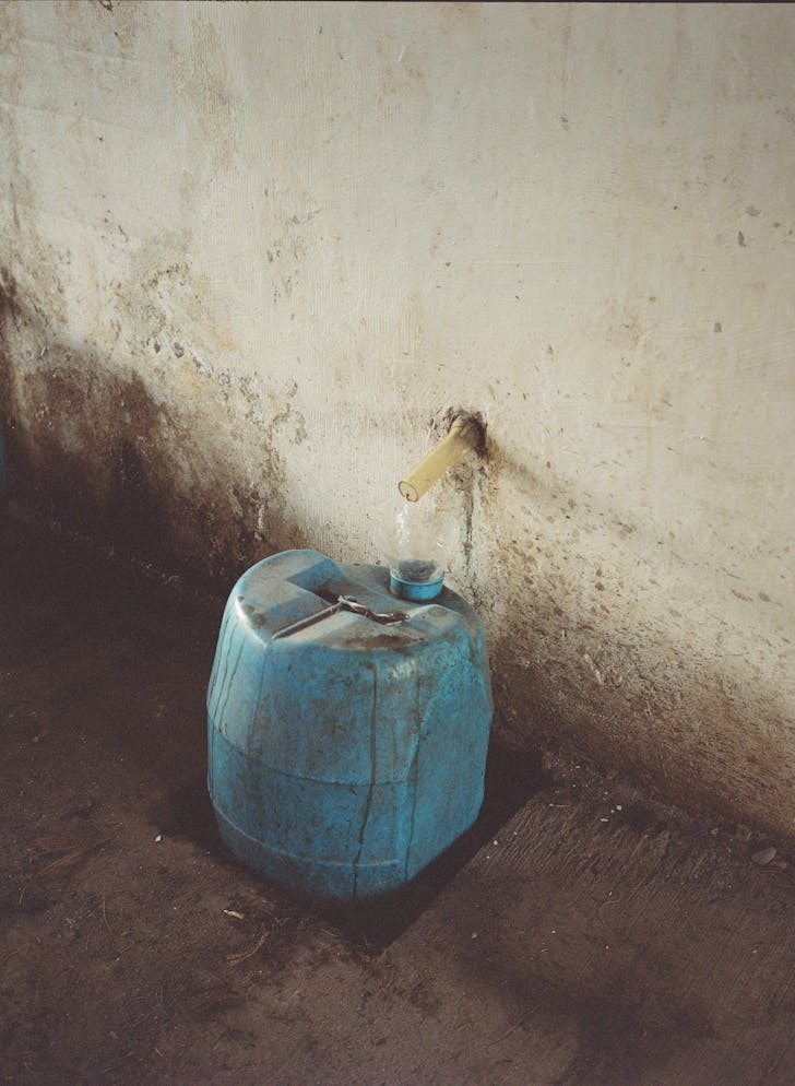 liquid pouring from a wall into a bucket through a tap head