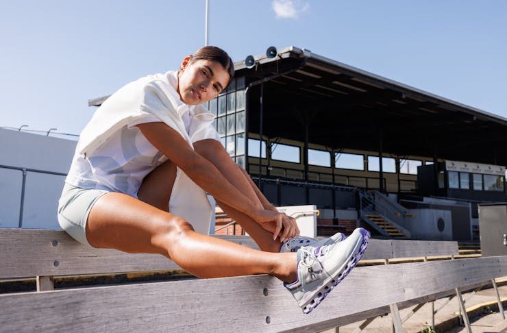 Women sitting in a stadium in gym gear and running shoes.