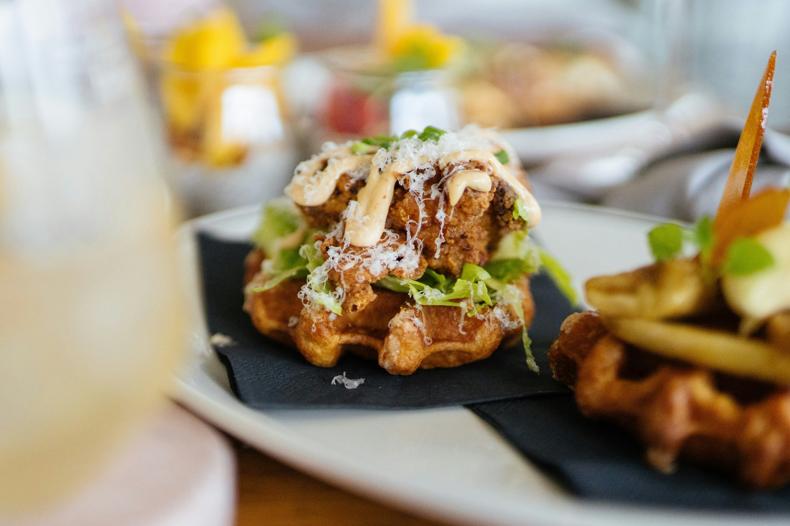 Fried chicken donut sliders with maple syrup and jalapenos on a table. 