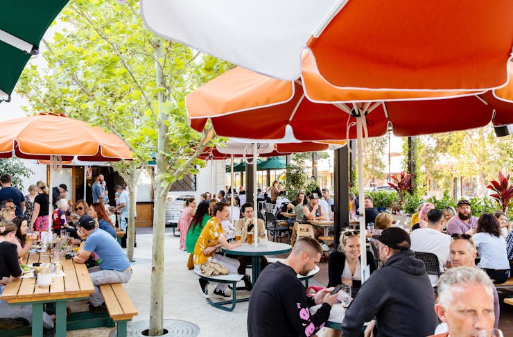 People sitting in a beer garden under umbrellas at a Perth pub. 