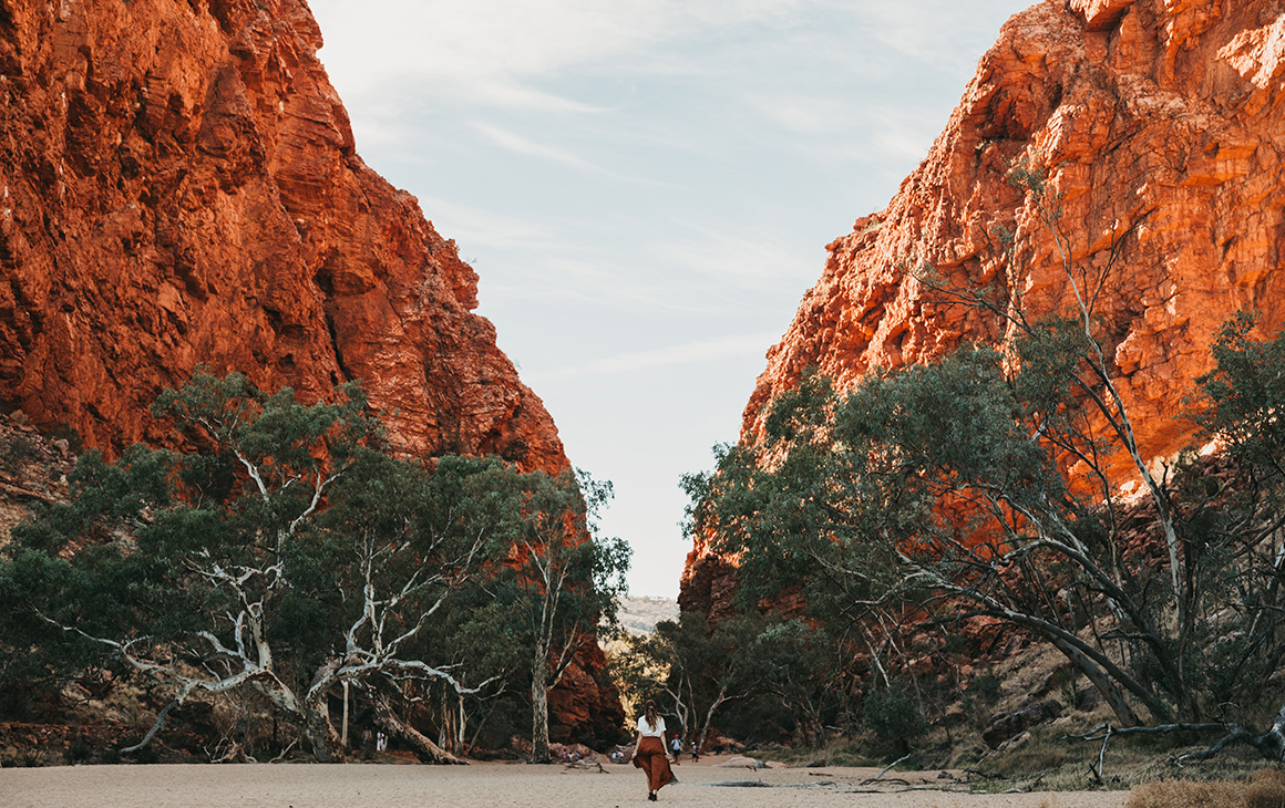 a woman walks between the stunning red rock walls of Simpsons Gap