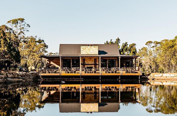 A country-style cottage on a picturesque body of water with a wrap-around verandah. 