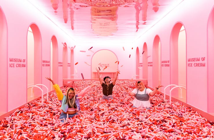 People in a giant ball pit filled with large sprinkle at the Museum of Ice Cream.