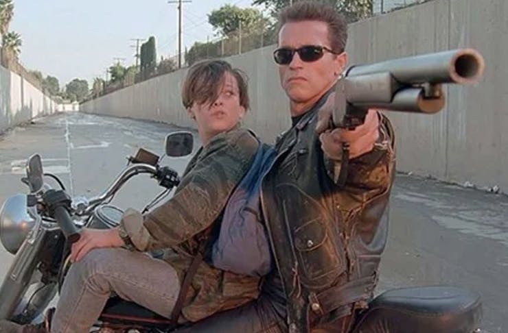two people on motorbike, one holding gun