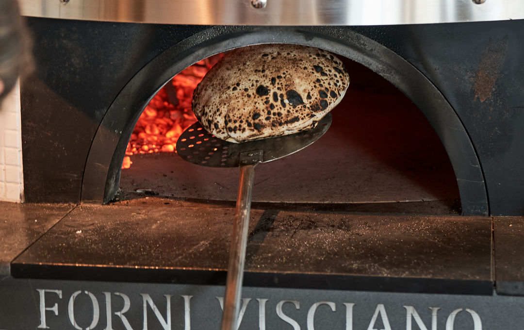 A pillowy piece of freshly-baked flatbread coming out of a wood-fire oven at a best restaurant Melbourne called Totti's