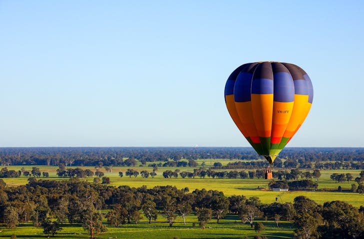 A scenic picture of a hot air balloon and green pastures.