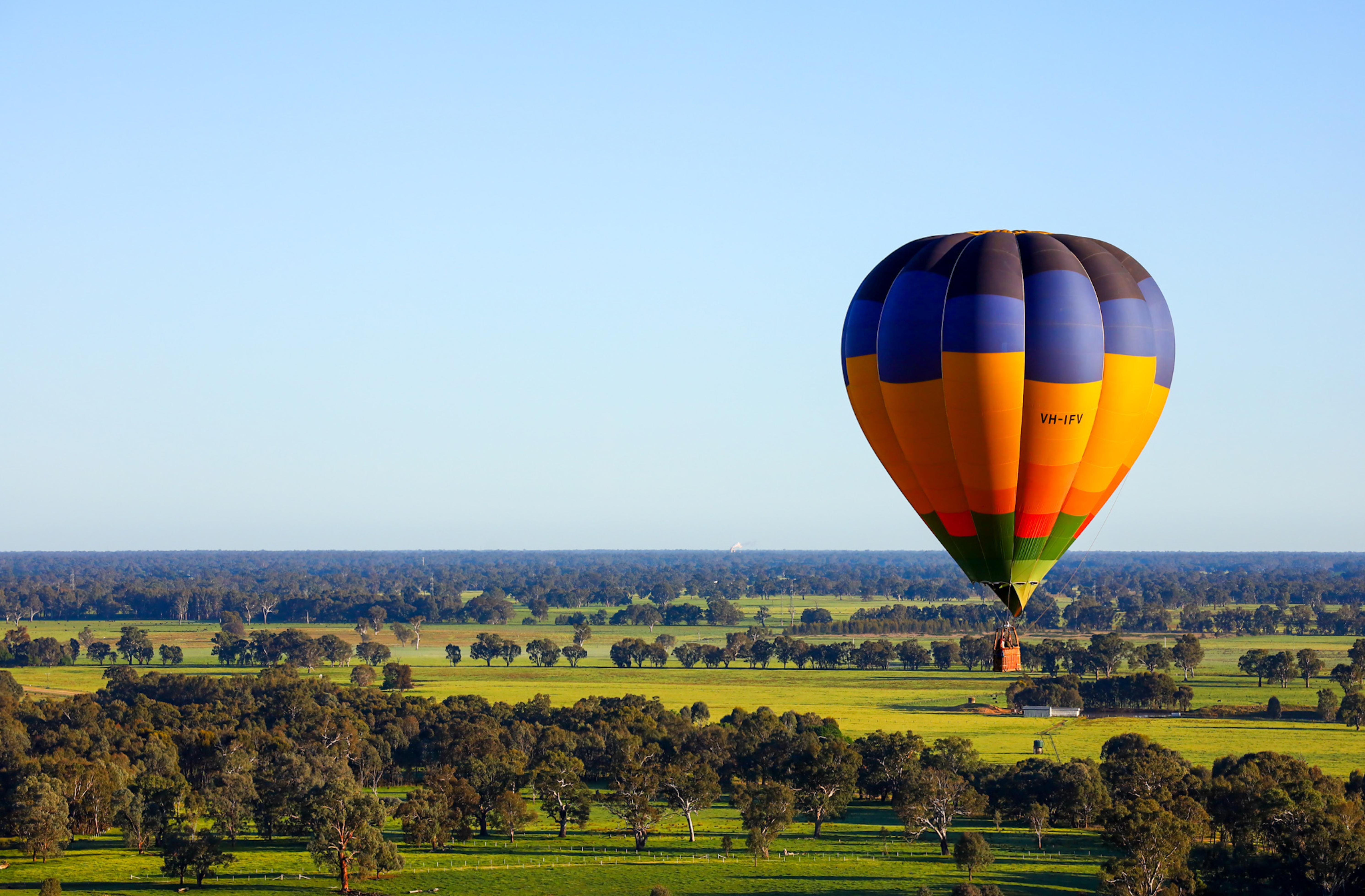 A scenic picture of a hot air balloon and green pastures.