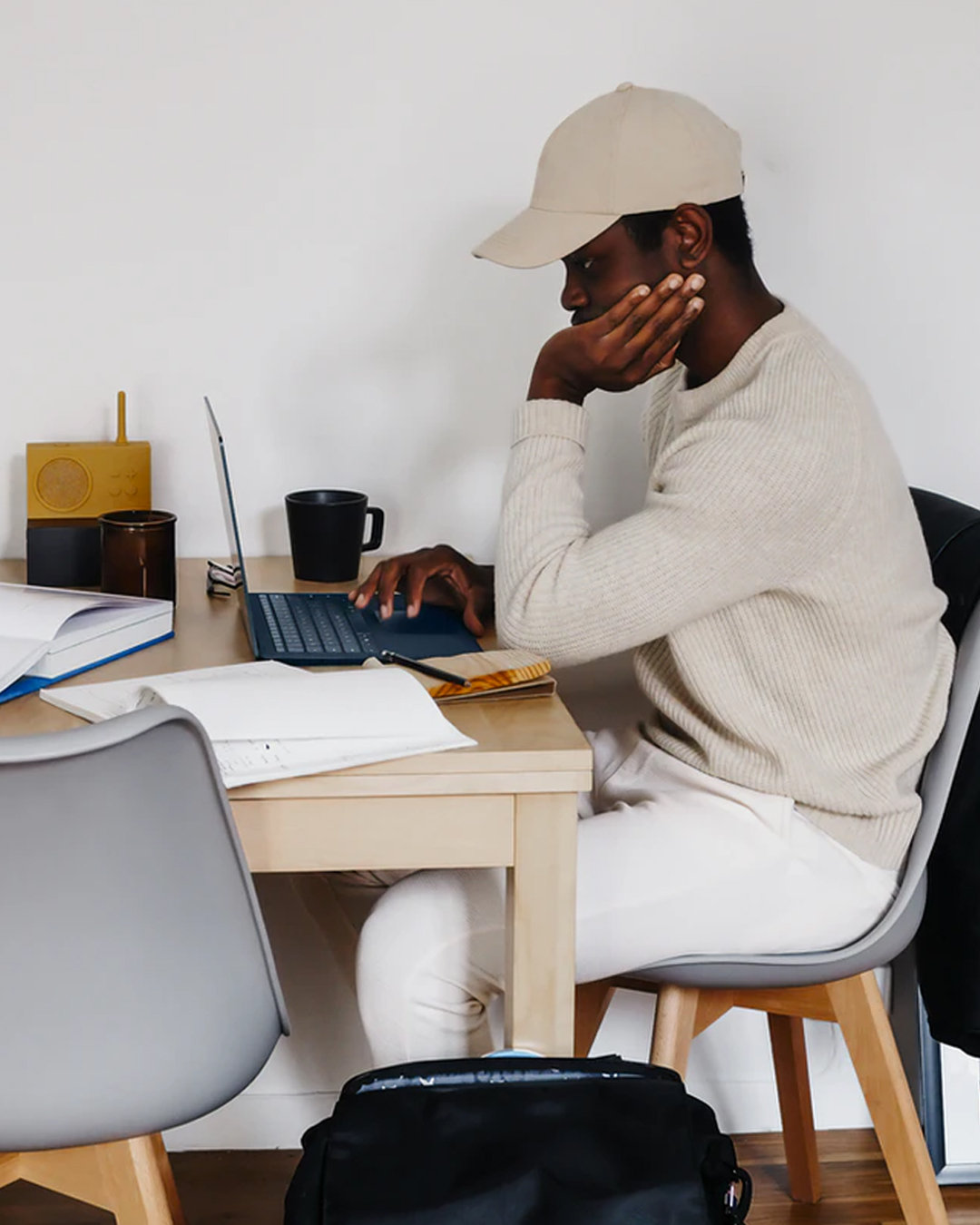 man sitting at desk wearing beige cap and typing