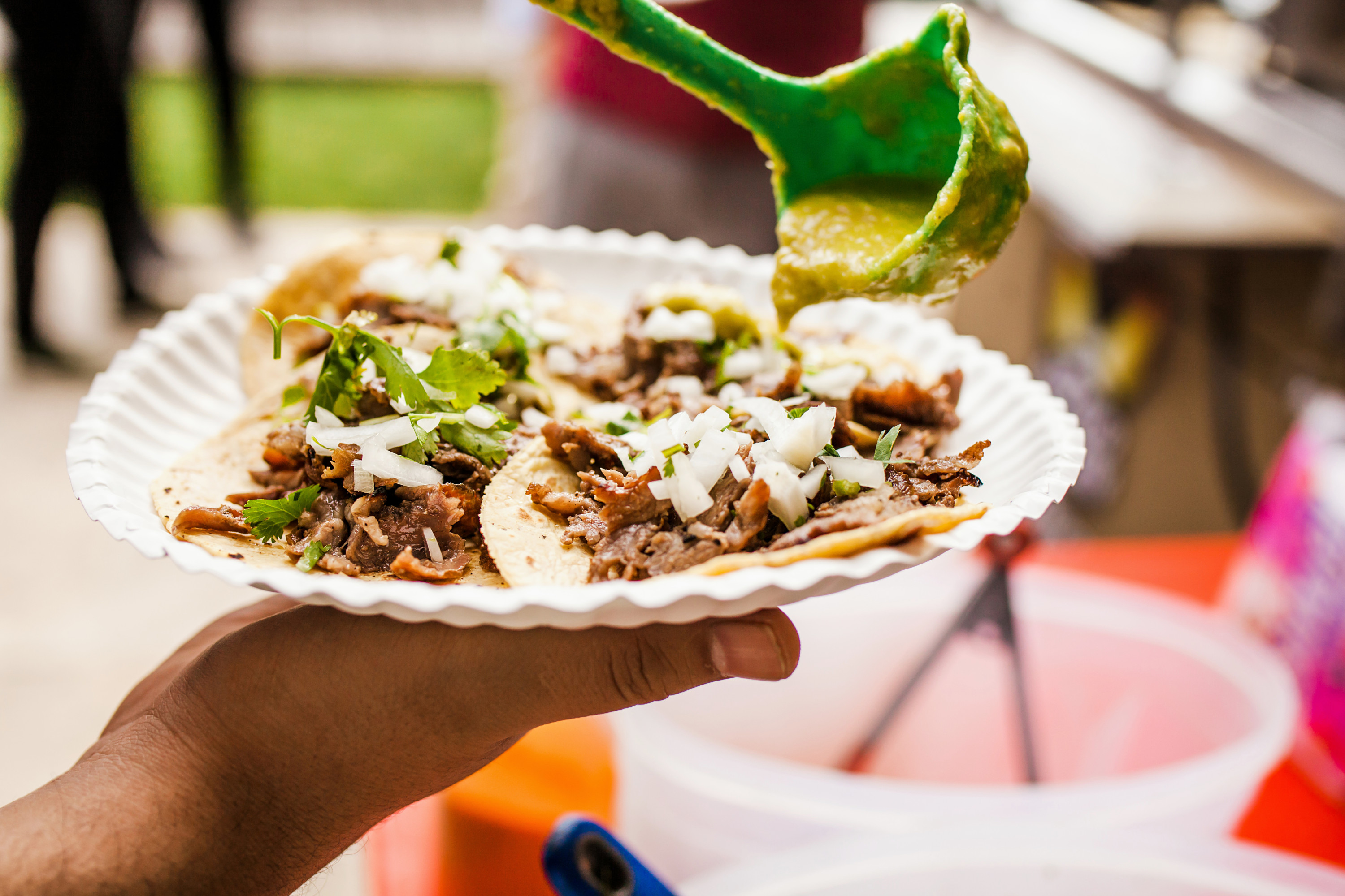 someone holding a paper plate with tacos on it