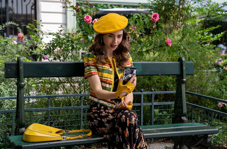a woman in a yellow beret stares at her phone