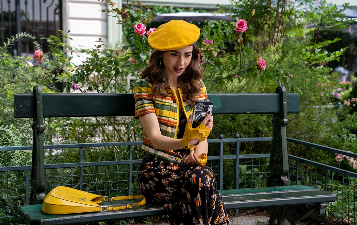 a woman in a yellow beret stares at her phone