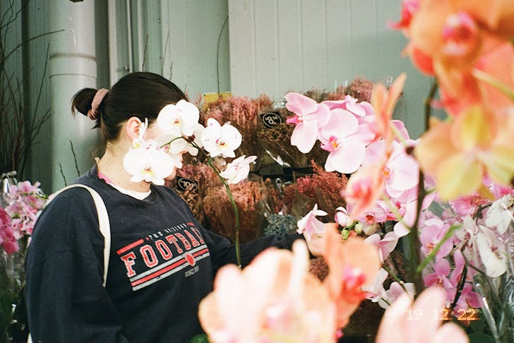 a woman's face is obscured by a cluster of flowers.