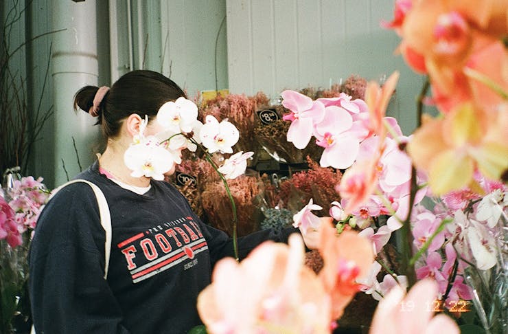 a woman's face is obscured by a cluster of flowers.