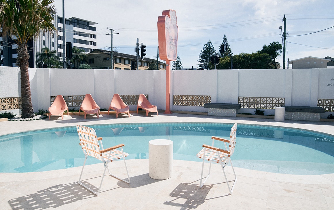 white and pink chairs sit around a blue pool