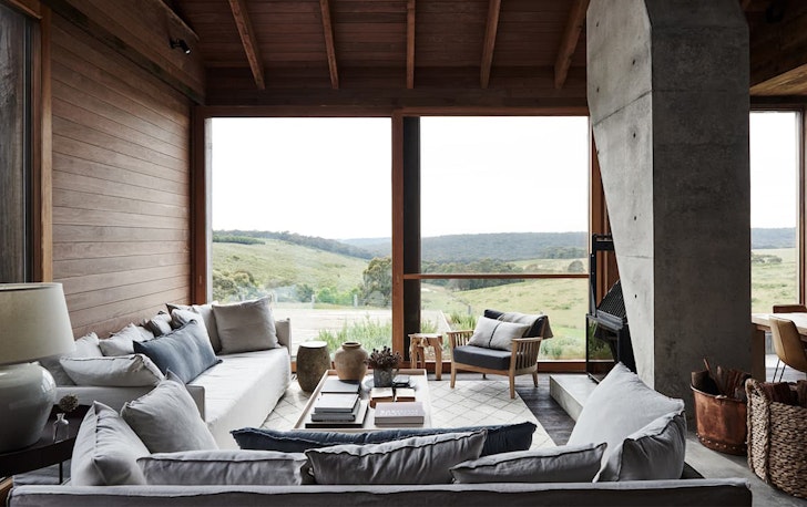 Two floor-to-ceiling windows are in a large living room with an L-shape couch.