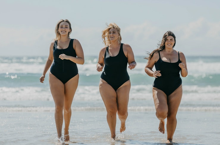 three women on the beach, running from the ocean into the shoreline