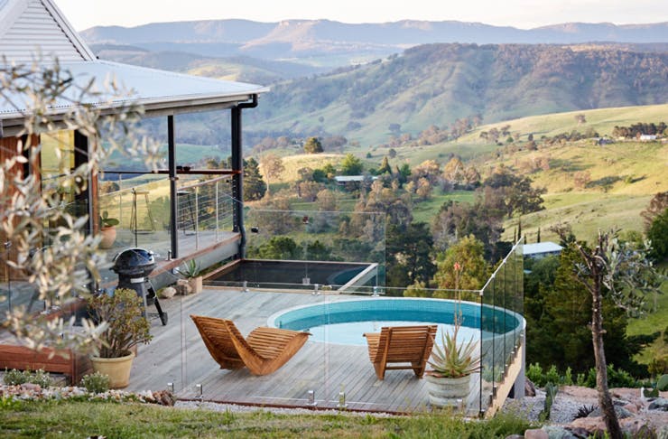 An Airbnb cabin with views across a green valley, and a plunge pool on the deck. 