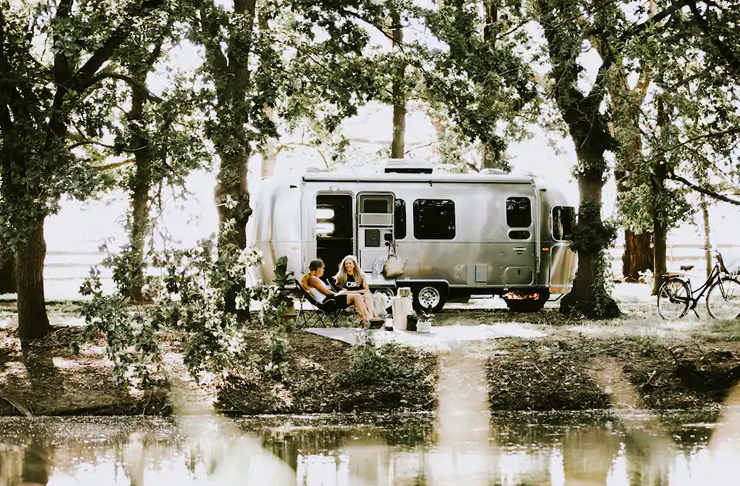 vintage airstream campervan parked near river