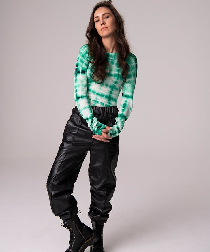 Amy Shark wears leather pants and a green stop.