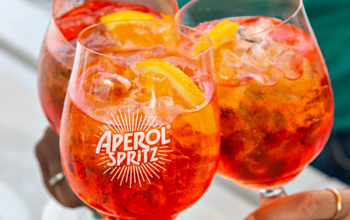 three bright orange Aperol Spritz cocktails.